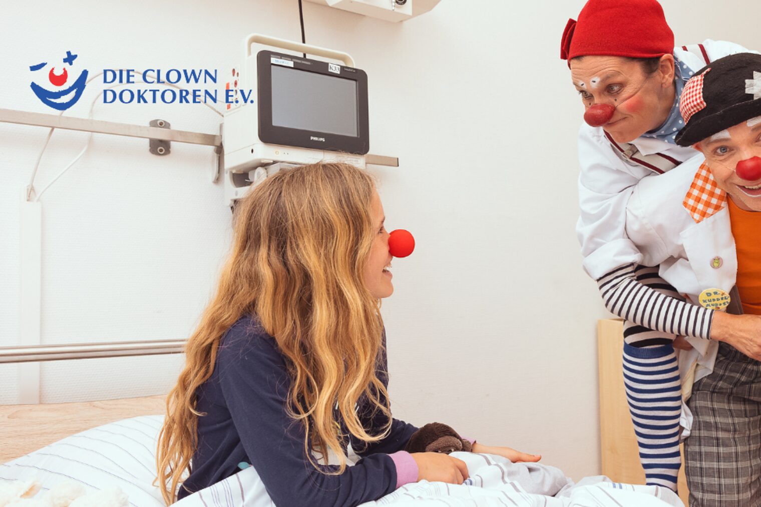 Die Clown Doktoren im Krankenhaus am Bett einer jungen Patientin.